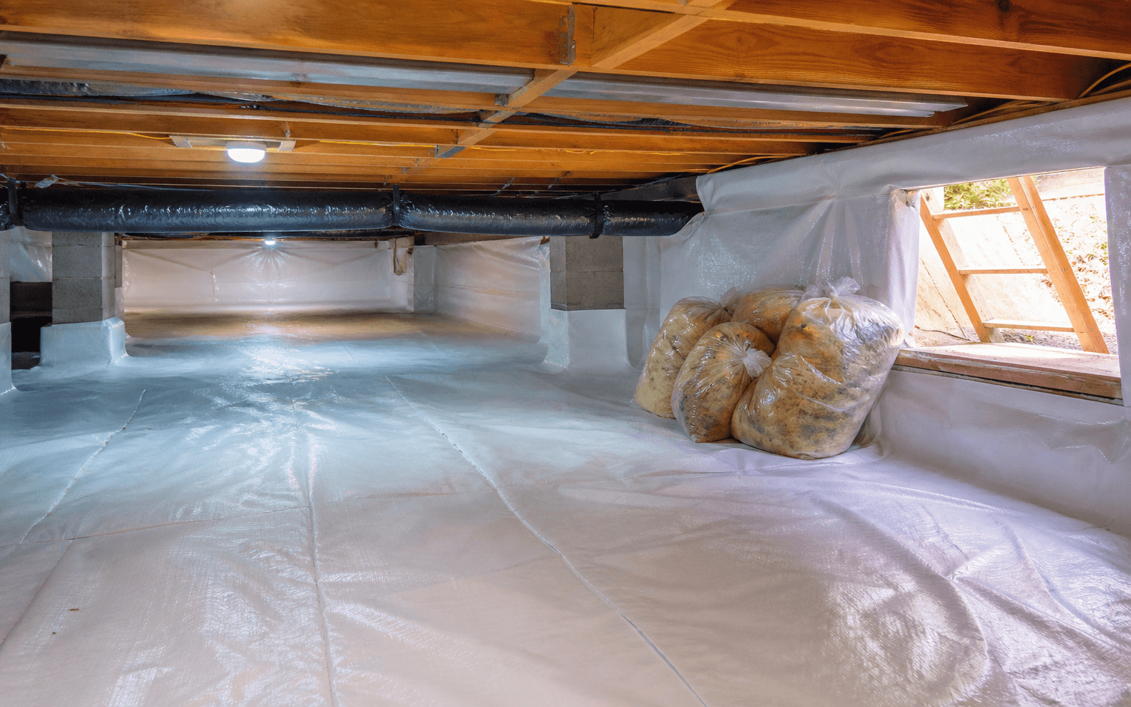 Clean crawl space with removed insulation bagged near the access before replacement